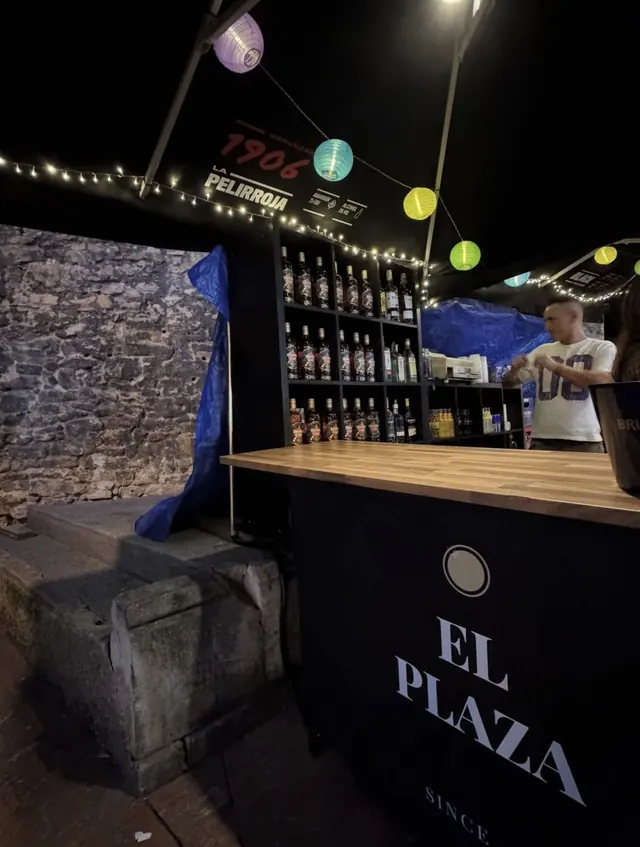 Chiringuito de El Plaza con farolillos de colores y estantes de botellas