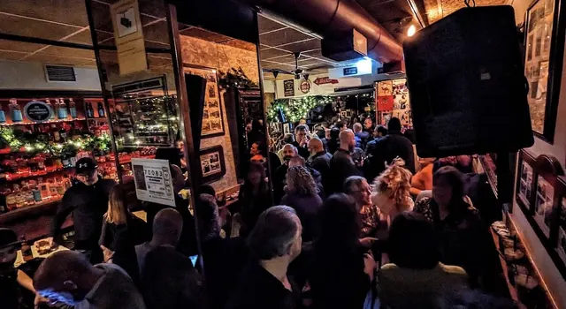 Interior de El Plaza lleno de gente, con botellas iluminadas y guirnaldas de luces